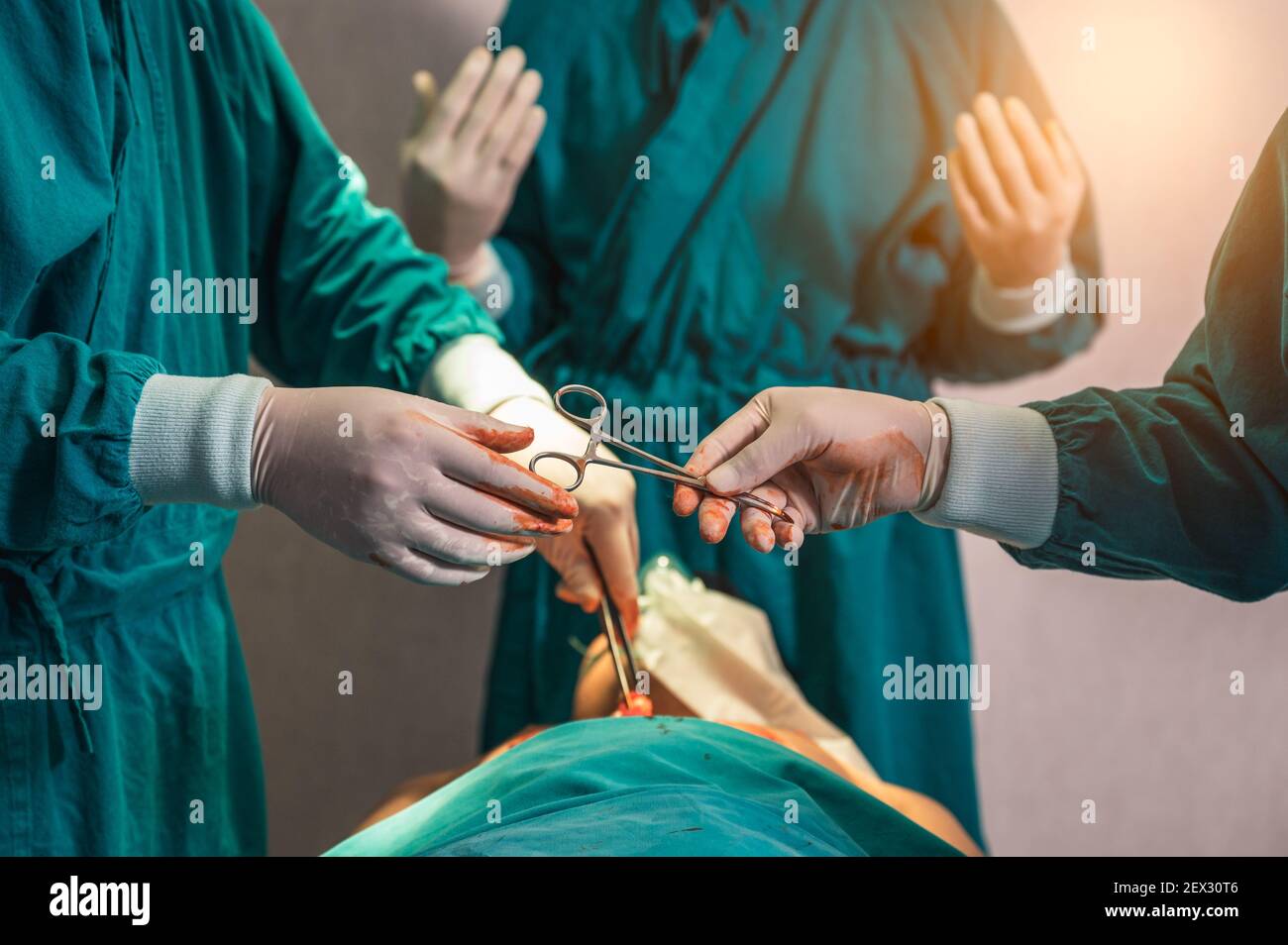 Chirurgen Team Durchführung einer Operation und Weitergabe chirurgische Schere auf verletzt Patient im Operationssaal des Krankenhauses Stockfoto