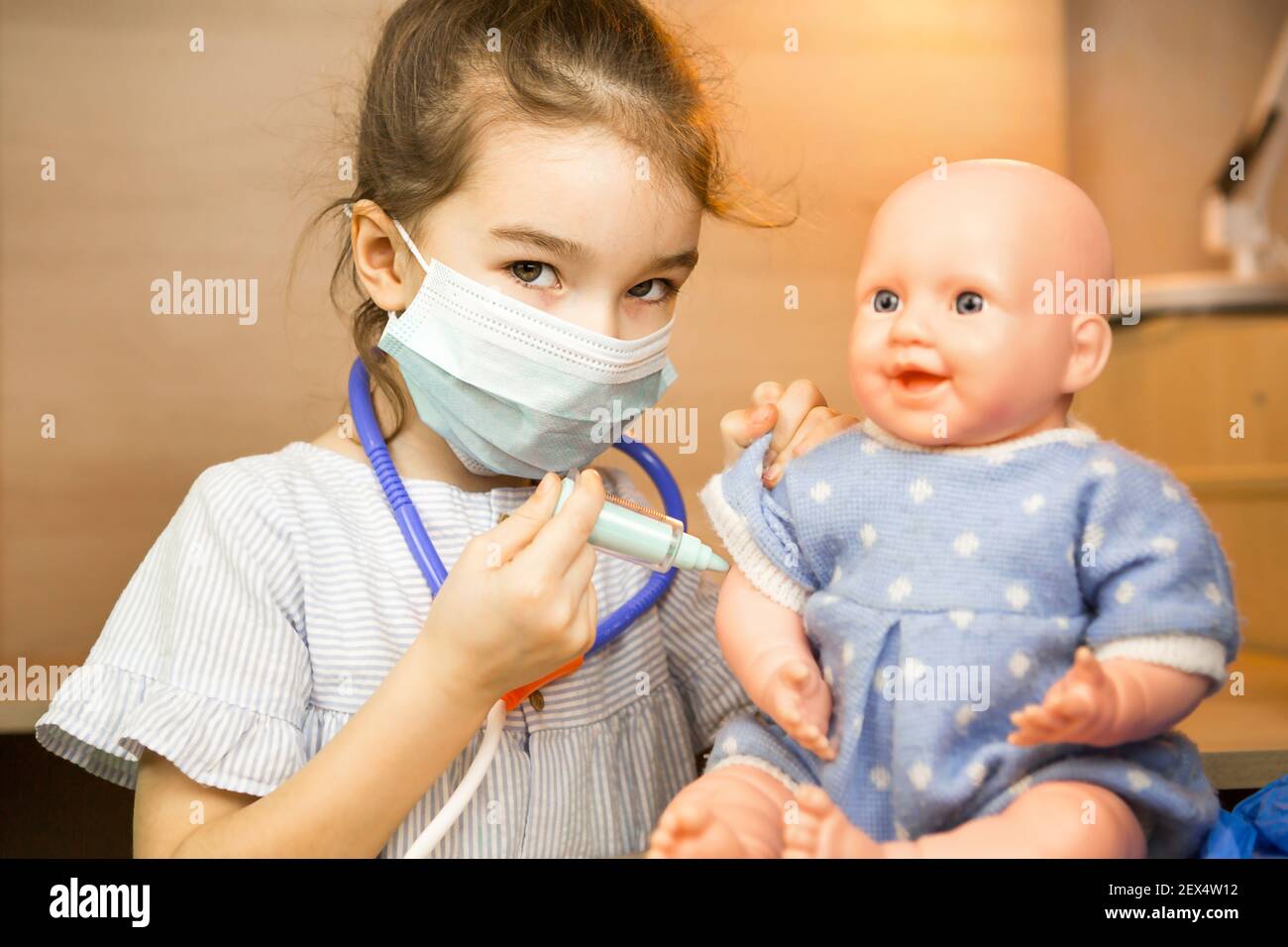 Ein Mädchen mit einer Puppe spielt Arzt, macht eine Spritze Impfung in der  Hand. Impfung, Impfkalender, Impfstoff, Berufsspiel. Injecti der  Krankenschwester Stockfotografie - Alamy