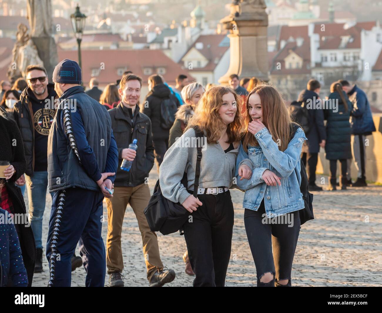 Prag, Tschechische Republik. 03-02-2021. Zwei junge schöne Frauen, die auf der Karlsbrücke im Stadtzentrum von Prag spazieren, reden und Spaß haben Stockfoto