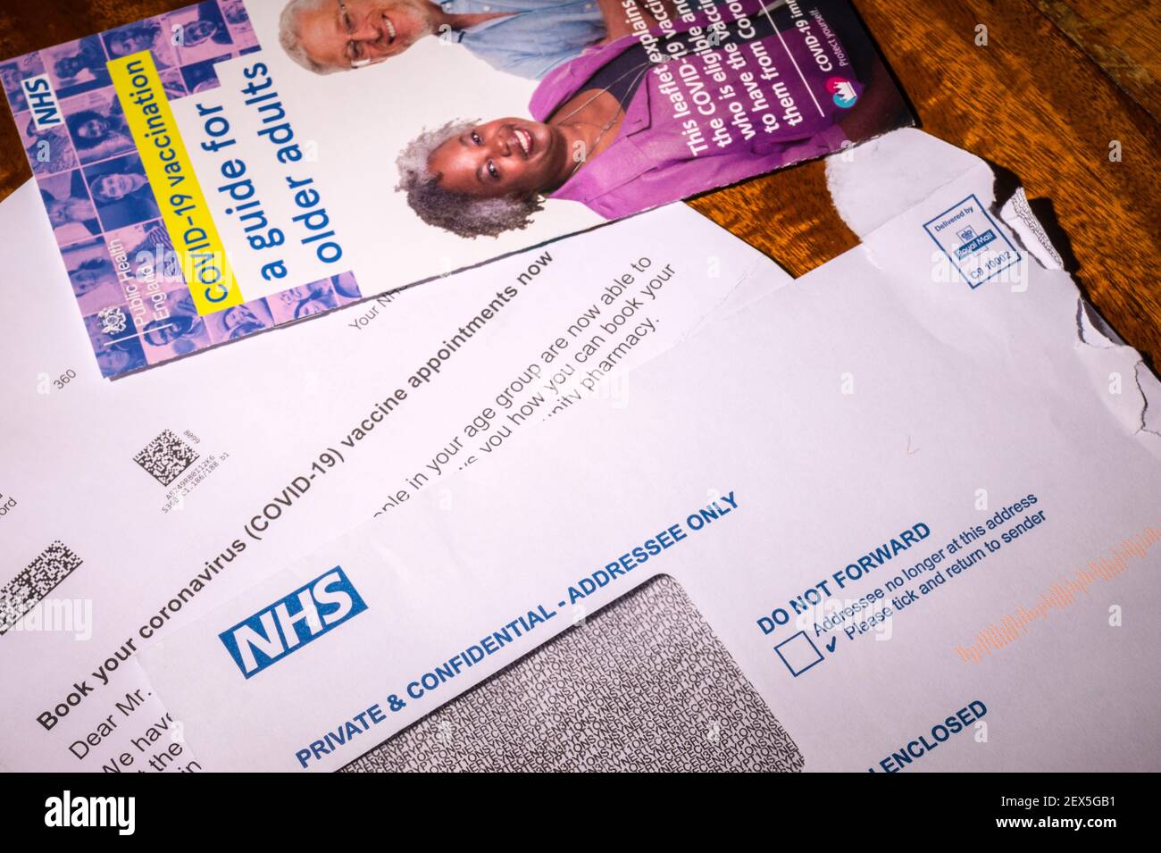 NHS Einladungsschreiben zur Buchung einer Coronavirus-Impfung für eine Person über 60 Jahre mit Merkblatt. Retuschiert, um persönliche Informationen zu entfernen. Stockfoto