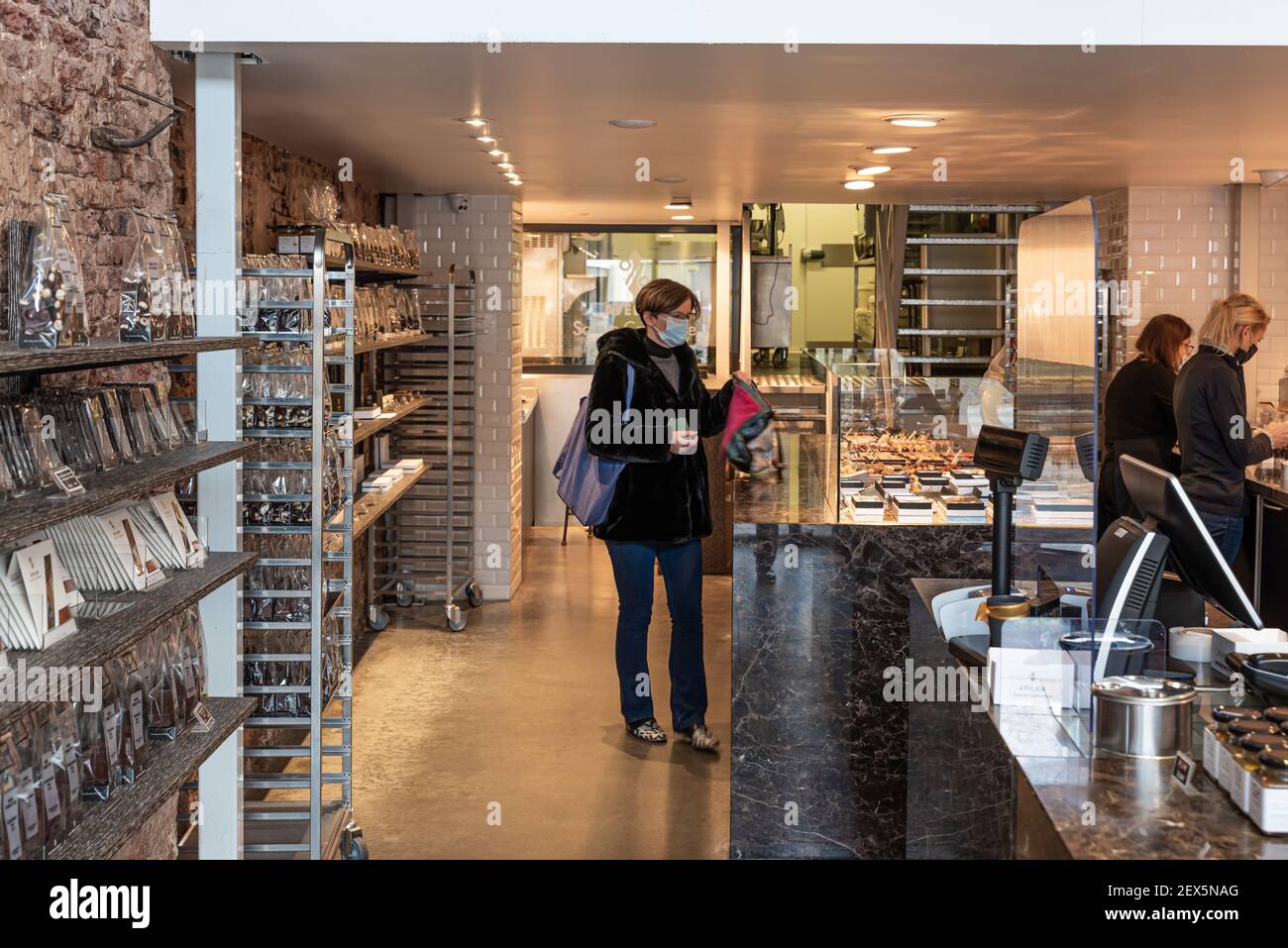 Attraktive Frau mit Mundmaske, Kauf Luxus-Schokolade Stockfoto