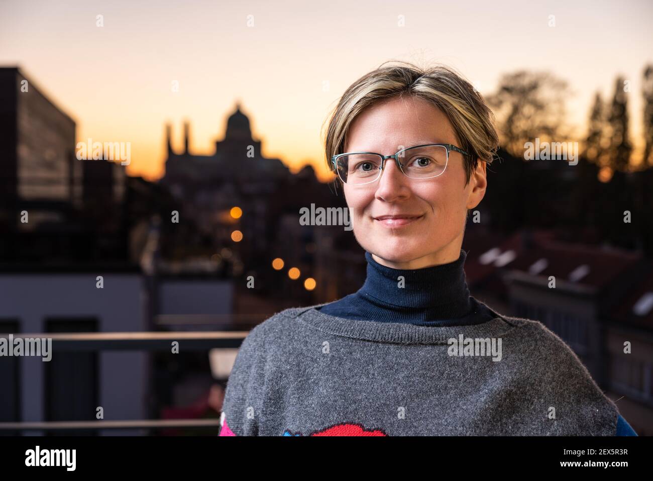 Porträt einer attraktiven dreißig Jahre alten weißen Frau posiert Auf einer Terrasse mit einem bunten Sonnenuntergang Hintergrund Stockfoto