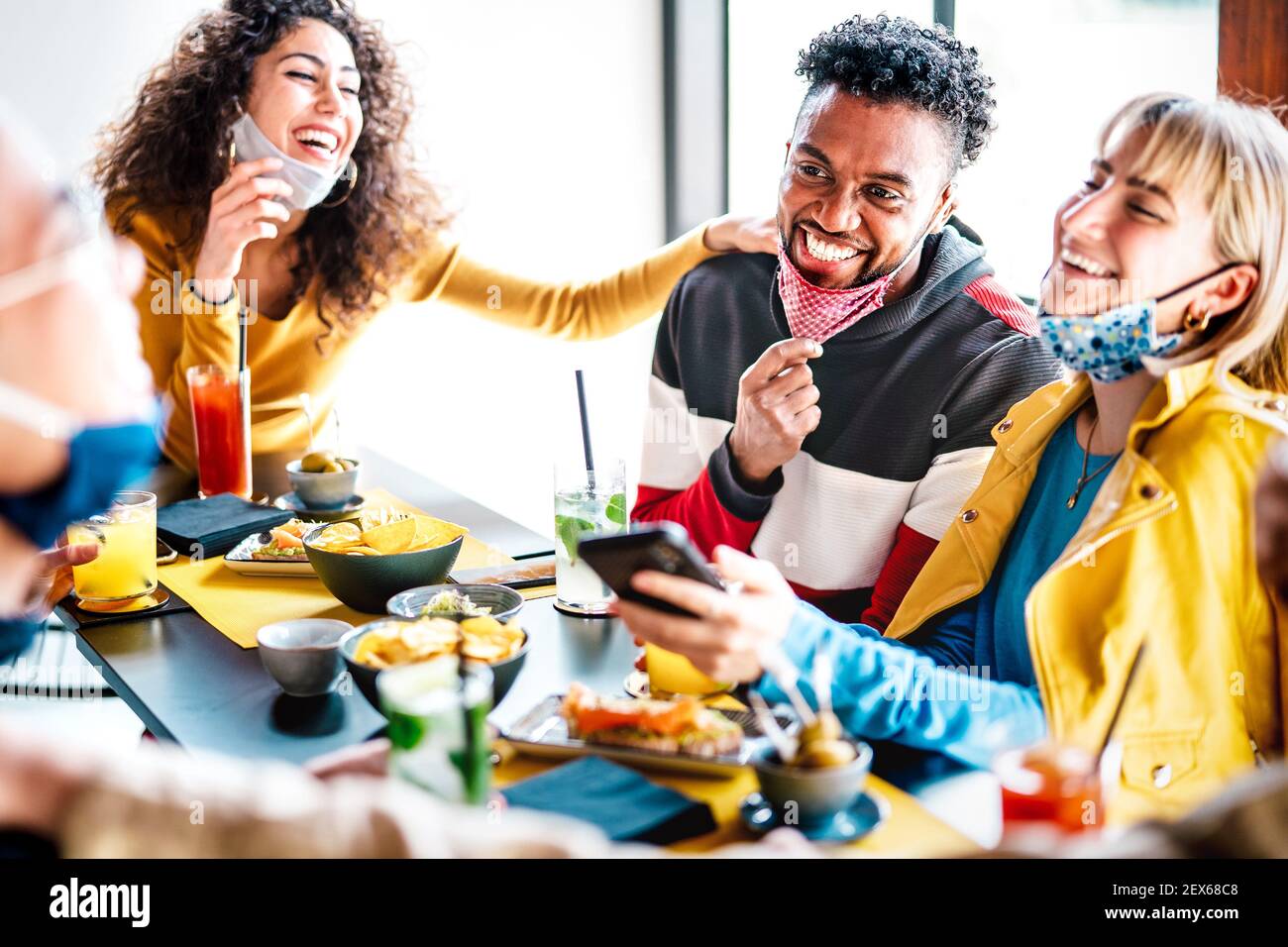 Freunde, die Spaß haben, an der Cocktailbar zu trinken - Menschen mit vielen Rassen Gemeinsame Gespräche bei der Wiedereröffnung des Restaurants - Neuer normaler Lebensstil Konzept Stockfoto