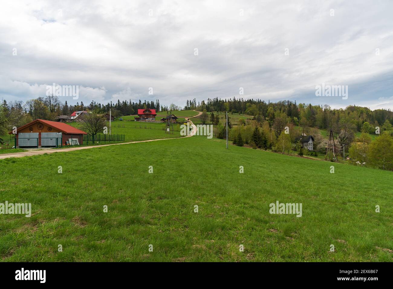 Ceslar Hügel in Slezske Beskydy Berge auf tschechisch - polnisch Grenzen mit Wiese, wenige Häuser und Bäume im Frühling Stockfoto