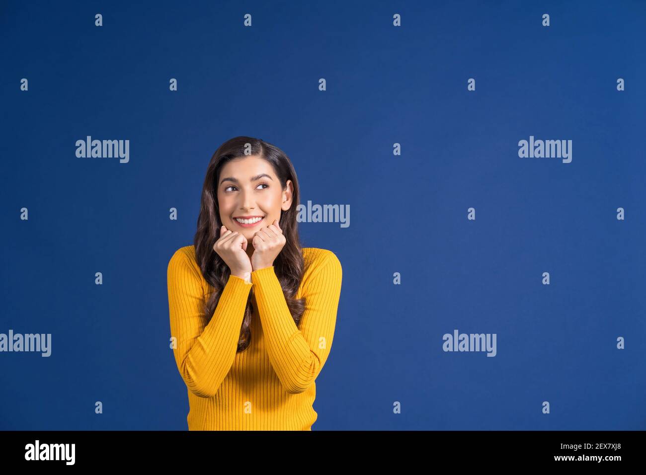 Glücklich junge asiatische Frau in bunten gelben Farbe Freizeitkleidung spannend und suchen, um Platz auf blauem Hintergrund kopieren, Lifestyle und Freizeit, tr Stockfoto