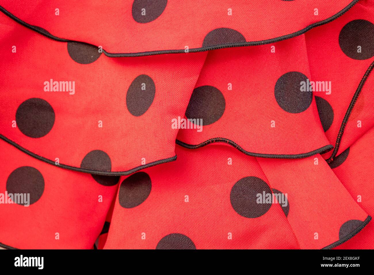 Eine Nahaufnahme der Deatil und Dekoration auf einem Flamenco-Kleid mit schwarzen Flecken auf rotem Hintergrund Stockfoto