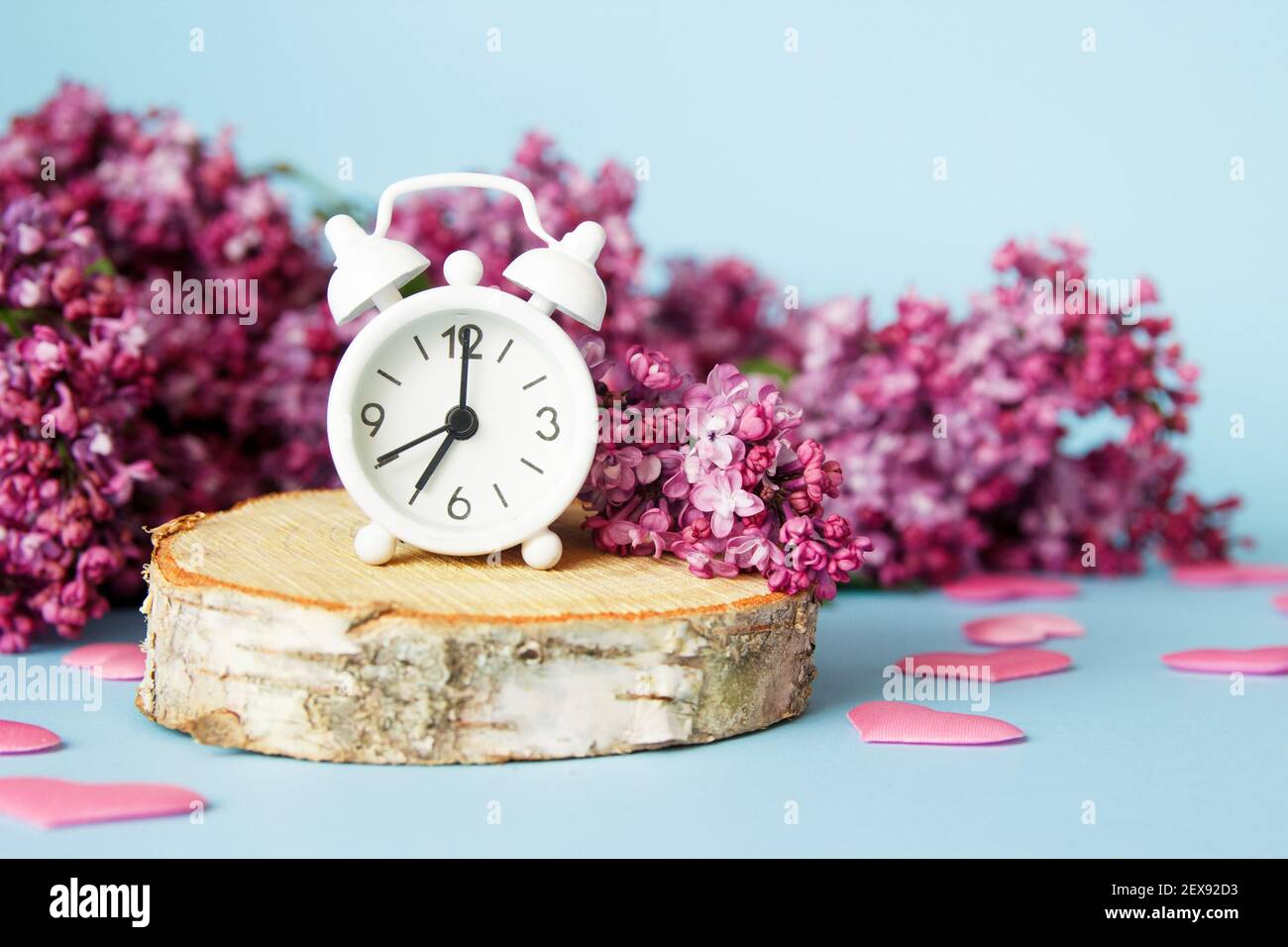 Flieder Blumen mit vintage winzig Wecker auf blauem Hintergrund. Frühlingshafte Morgenkonzeption. Stockfoto