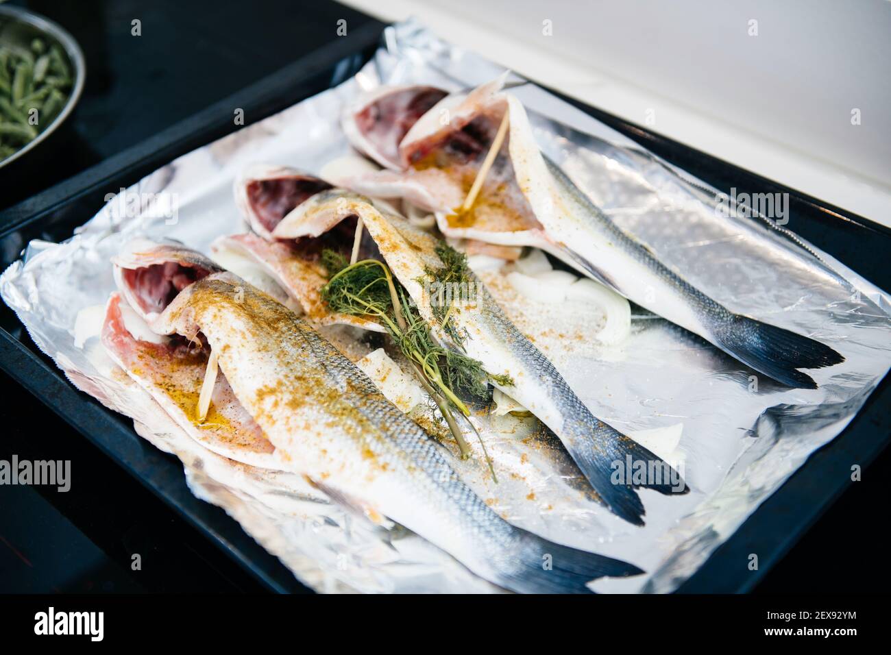 Blick von oben auf drei Bass Lateolabrax japonicus Fisch bereit In den Ofen gehen gewürzt mit verschiedenen Zutaten - Bio Bio-mediterrane Rezept Stockfoto
