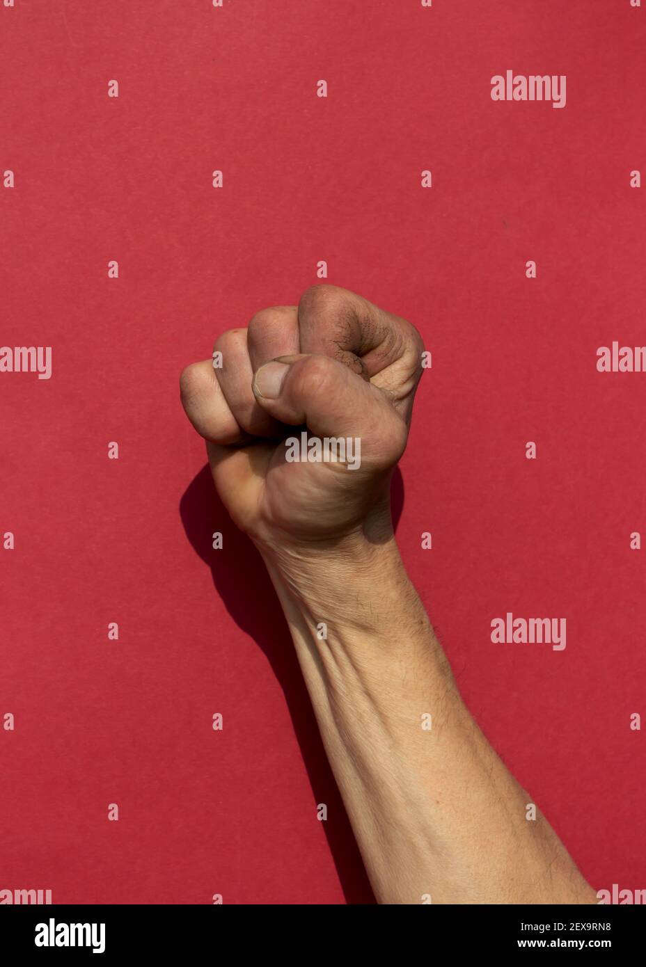 Swarthy raue mans Hand mit geballter Faust auf rotem Hintergrund. Cesar Chavez Day Konzept. Vertikale Aufnahme. Stockfoto
