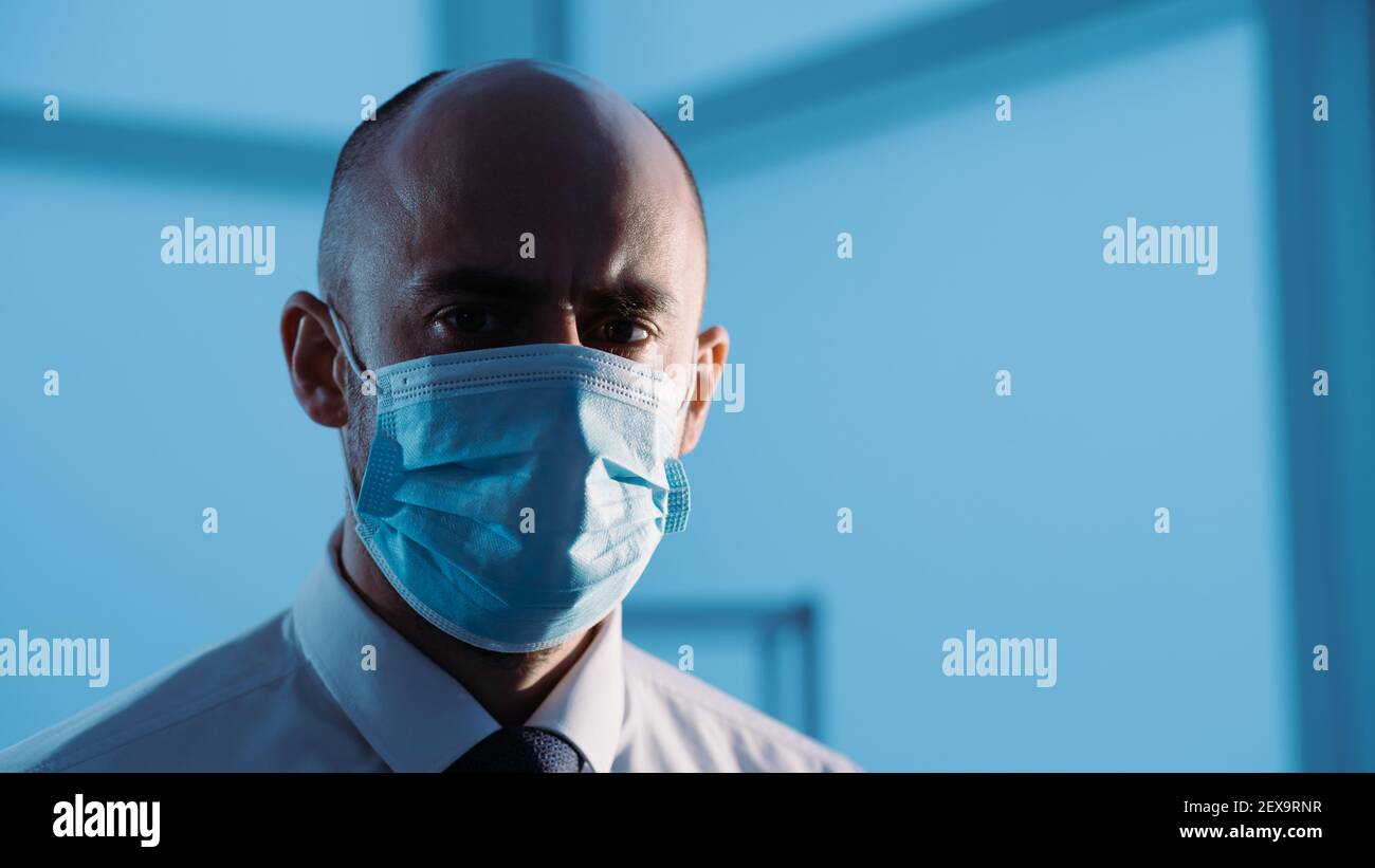 Ernsthafter Mann in einer Schutzmaske, der in der Arztpraxis steht. Stockfoto