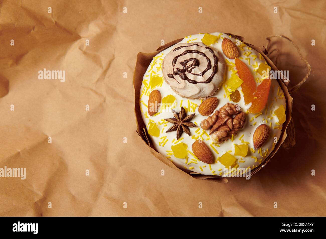 Schöne handgemachte Panettone mit flüssigen Puderzucker Mandeln, Walnuss und Baiser dekoriert. Brauner Papierhintergrund. Süße Osterkuchen oh Feiertage. Stockfoto