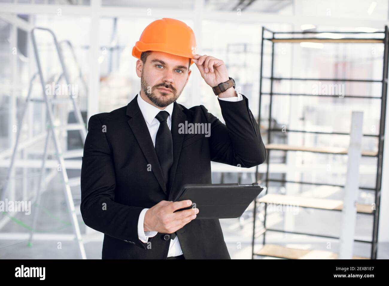 Fokussierter Mann in Anzug und Hardhat mit Tablet bei der Arbeit Stockfoto