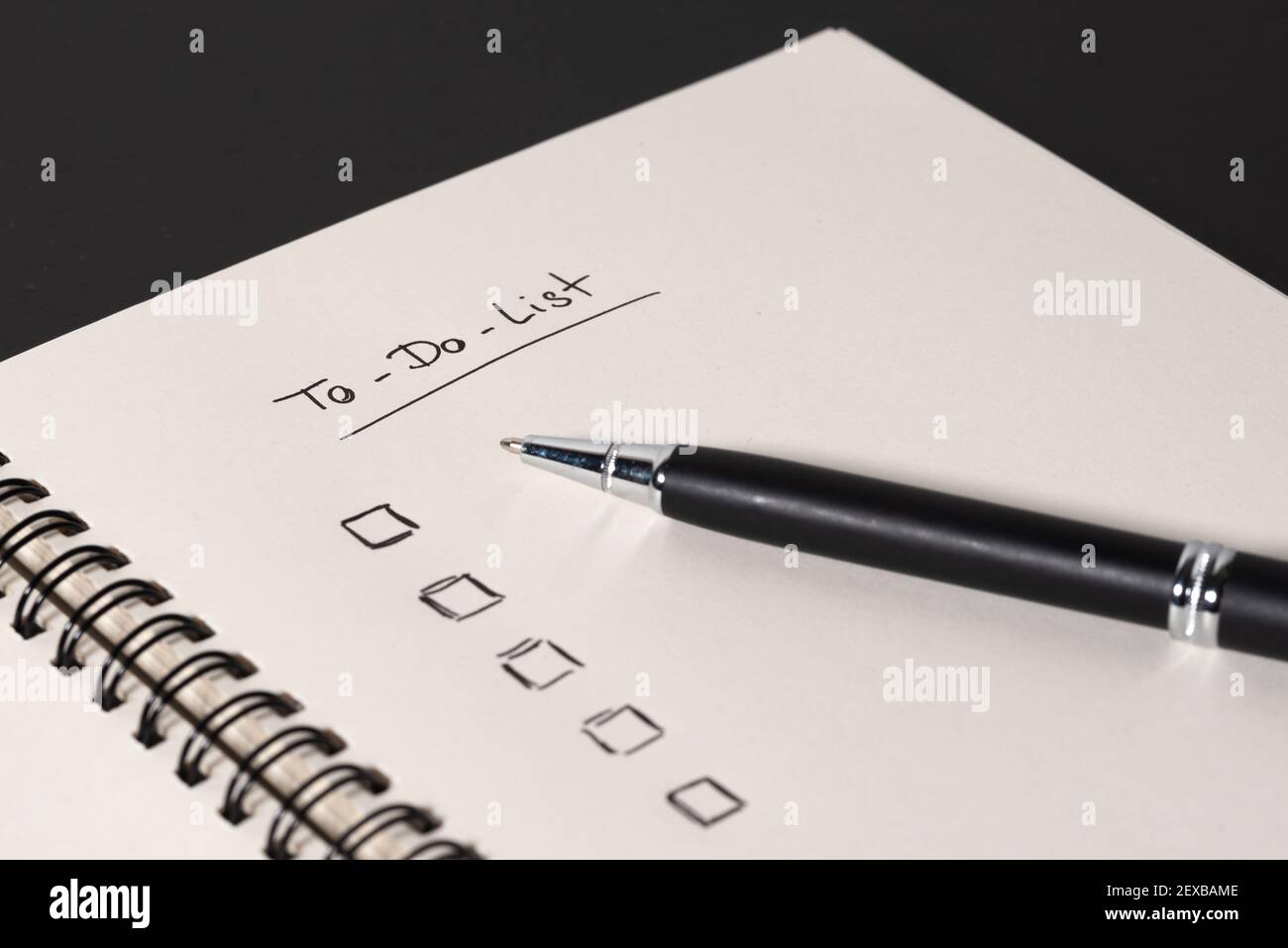 High-Angle-Ansicht der handschriftlichen To-Do-Liste auf Spirale Notizblock auf dunklem Schreibtischhintergrund Stockfoto