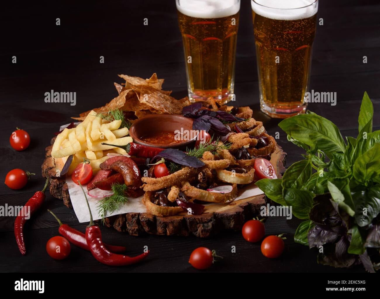 Ein großer Teller mit einer großen Auswahl an Biersnacks auf einem Holzbrett vor dunklem Hintergrund. Stockfoto
