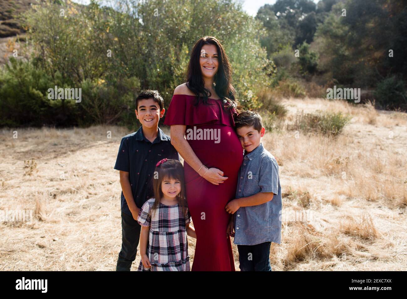 Schwangere Mutter posiert mit drei Kindern im Feld in San Diego Stockfoto