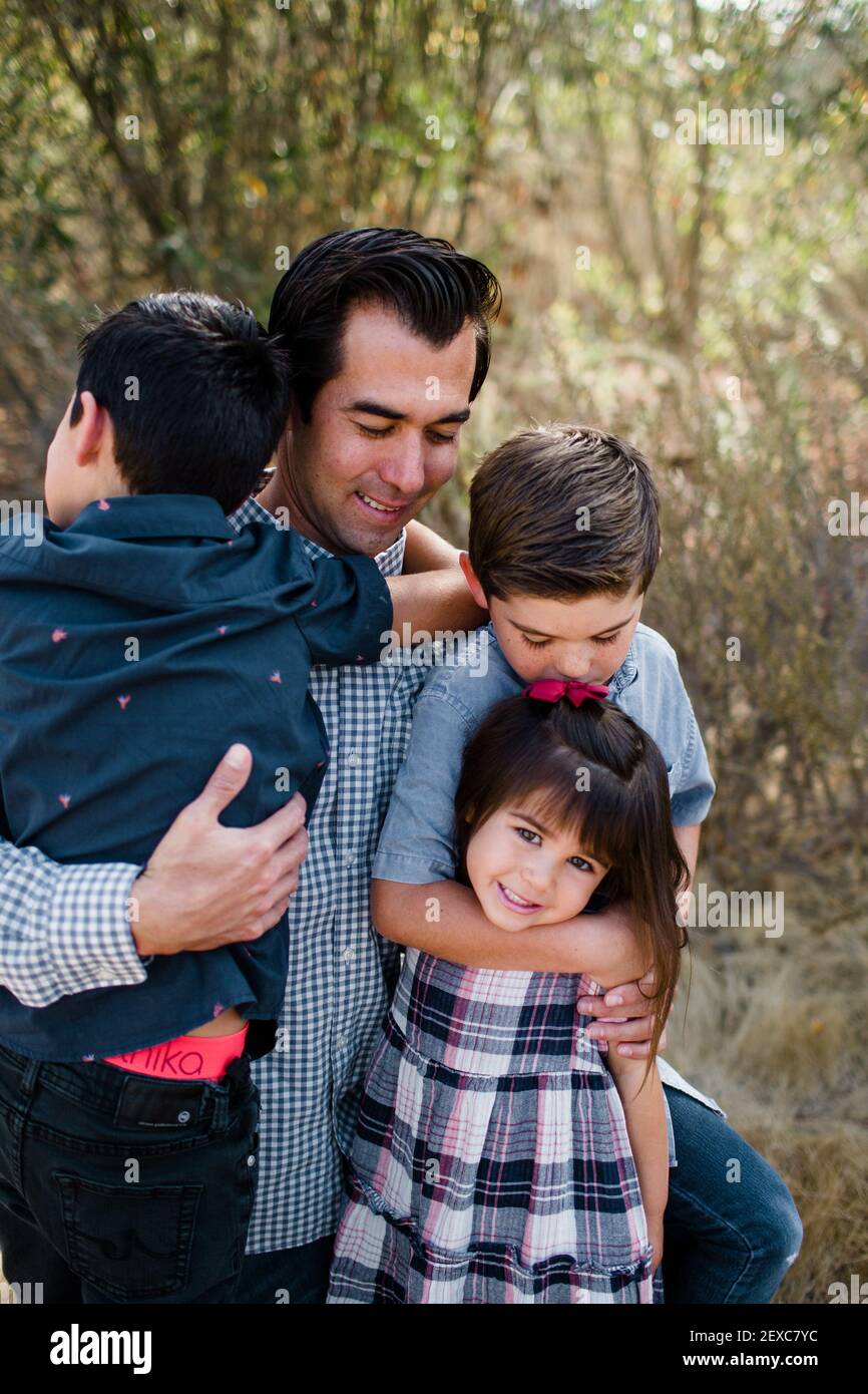 Vater hält drei Kinder im Feld in San Diego Stockfoto