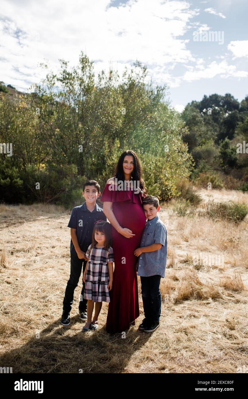 Schwangere Mutter posiert mit drei Kindern im Feld in San Diego Stockfoto