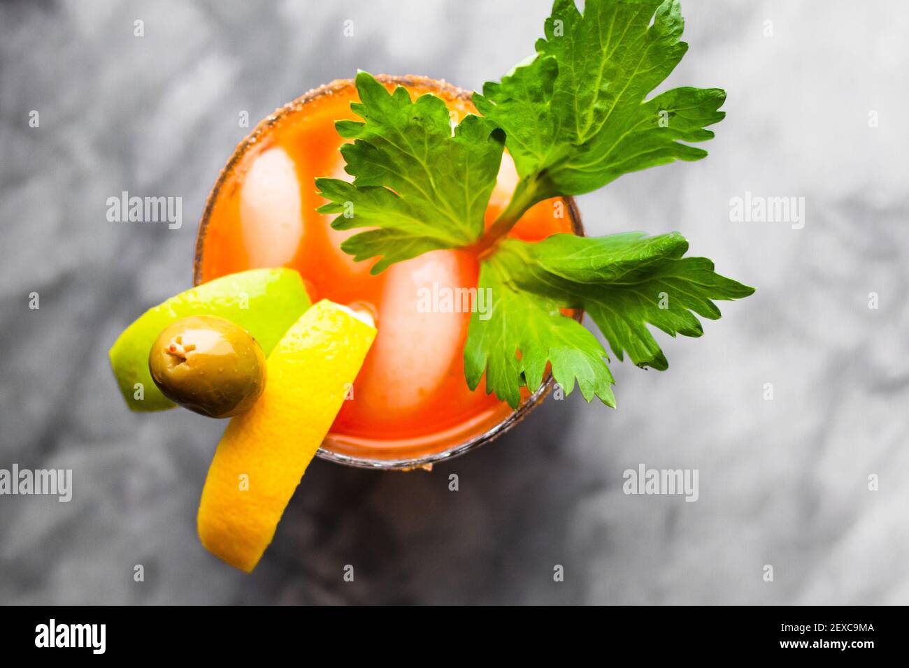 Ein Schuss Limette, Zitrone, Oliven und Petersilie garnierte Bloody Mary auf einer grauen Marmorplatte. Stockfoto