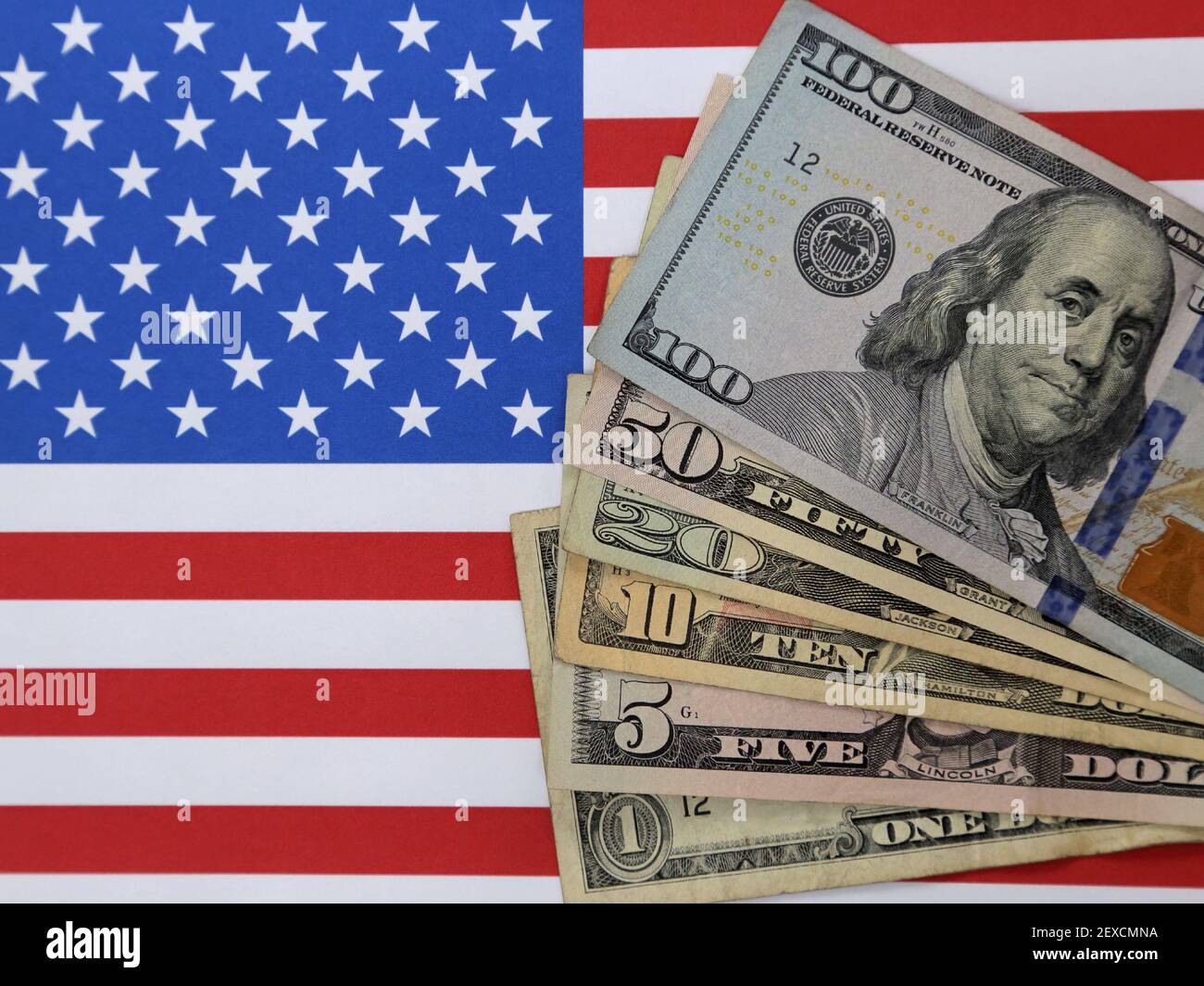 Stückelungen der USA 1, 5, 10, 20, 50, Und 100-Dollar-Scheine werden auf den roten, weißen und blauen Sternen und Streifen einer amerikanischen Flagge gezeigt. Stockfoto