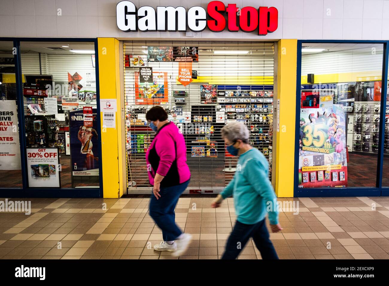 Mall Walkers flanieren an einem geschlossenen und verlassenen Game Stop Store in der Berlin Mall, Berlin, VT, USA vorbei. Stockfoto