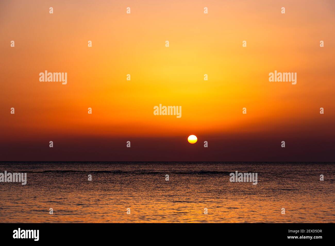 Heller Sonnenuntergang mit einer großen gelben Sonne unter der Meeresoberfläche. Stockfoto