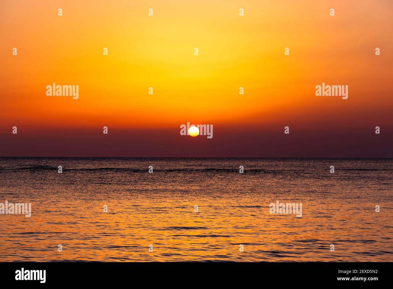 Heller Sonnenuntergang mit einer großen gelben Sonne unter der Meeresoberfläche. Stockfoto