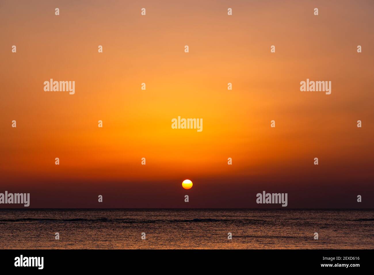 Heller Sonnenuntergang mit einer großen gelben Sonne unter der Meeresoberfläche. Stockfoto