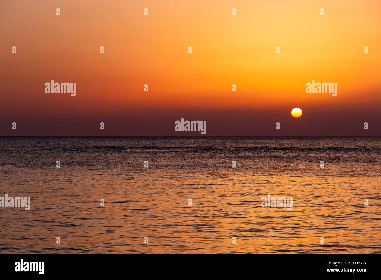 Heller Sonnenuntergang mit einer großen gelben Sonne unter der Meeresoberfläche. Stockfoto