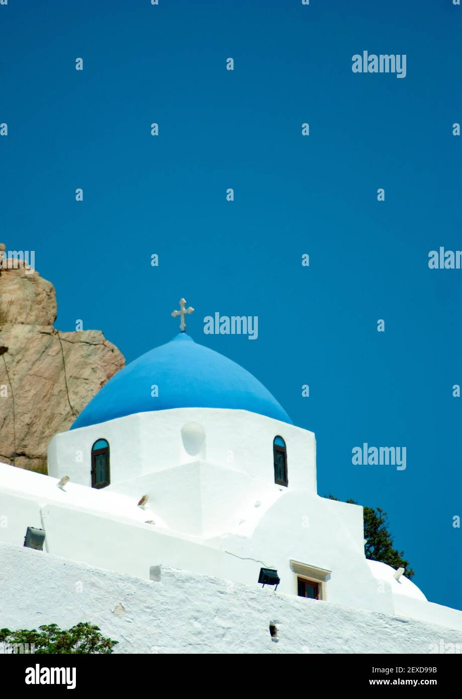 Ios, Griechenland. Schöne traditionelle Kapelle auf einem Hügel über dem alten Dorf der Inseln. Vertikale Ansicht mit hellblauem Himmel für den Kopierbereich. Detailreiche Aufnahme o Stockfoto