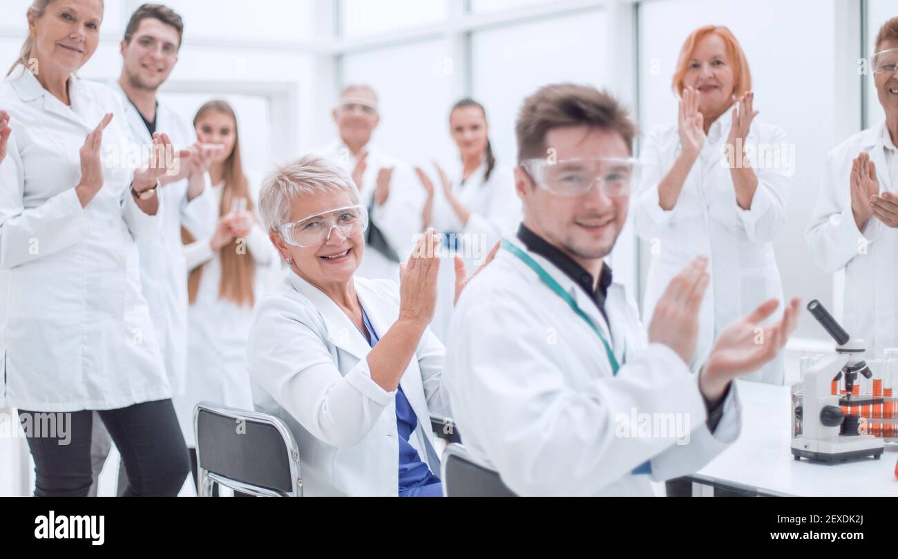 Eine Gruppe junger Wissenschaftler gratuliert ihrem Kollegen mit Applaus Stockfoto