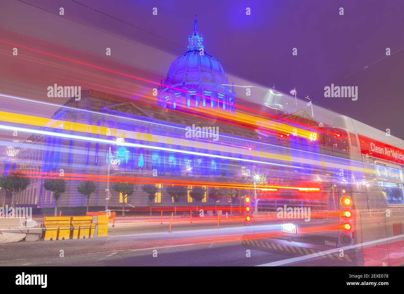 Der Elektrobus fährt auf der Straße vorbei, während das Rathaus von San Francisco blau leuchtet, um die Mitarbeiter des Gesundheitswesens während der COVID-19 Pandemie in Kalifornien, USA, zu ehren. Stockfoto