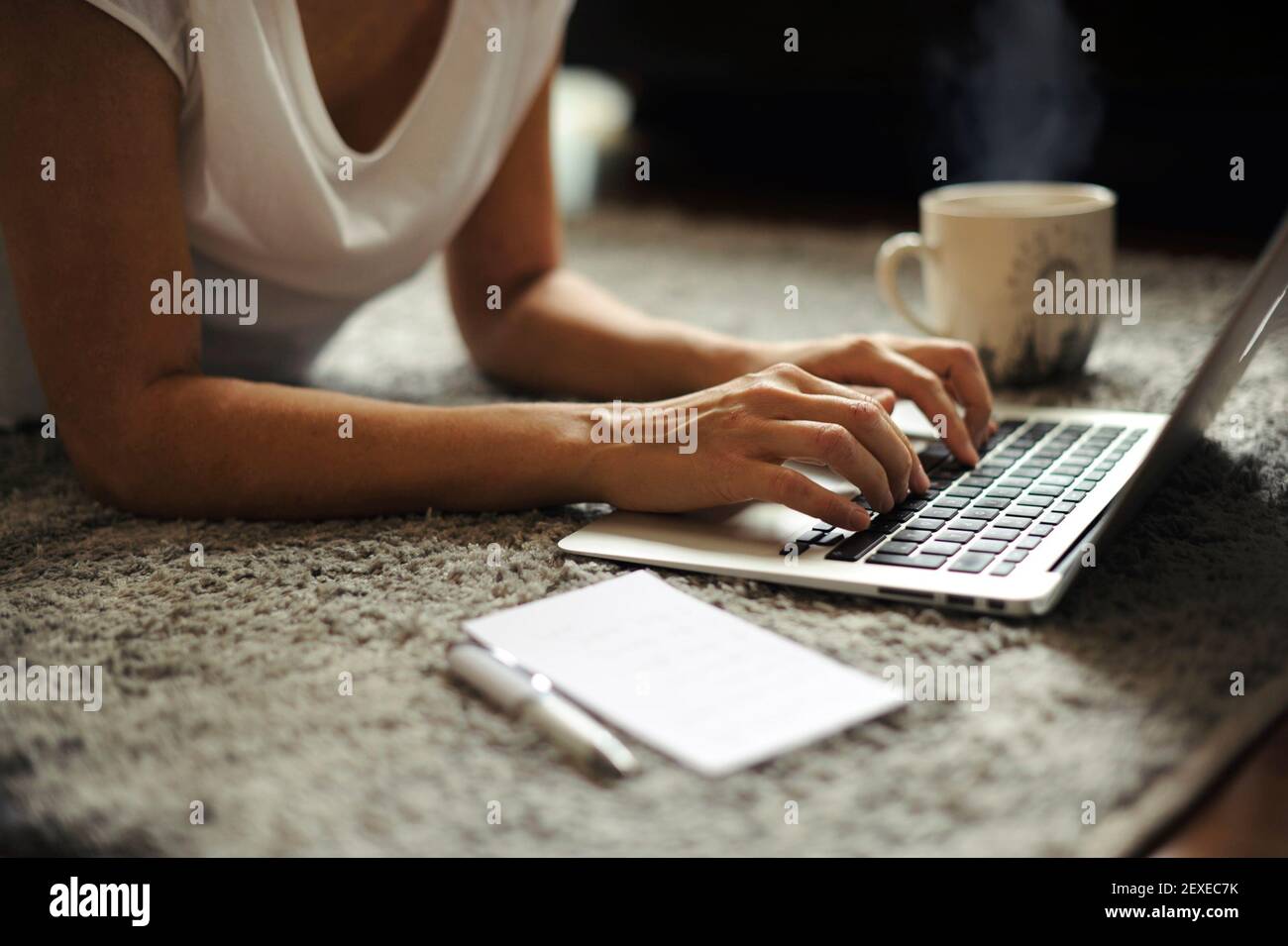 Nahaufnahme der Hände einer Frau, die an einem Laptop mit einer dampfenden Tasse heißem Getränk arbeitet. Telearbeit von zu Hause/ Start-up Lifestyle, weibliches Unternehmerkonzept Stockfoto
