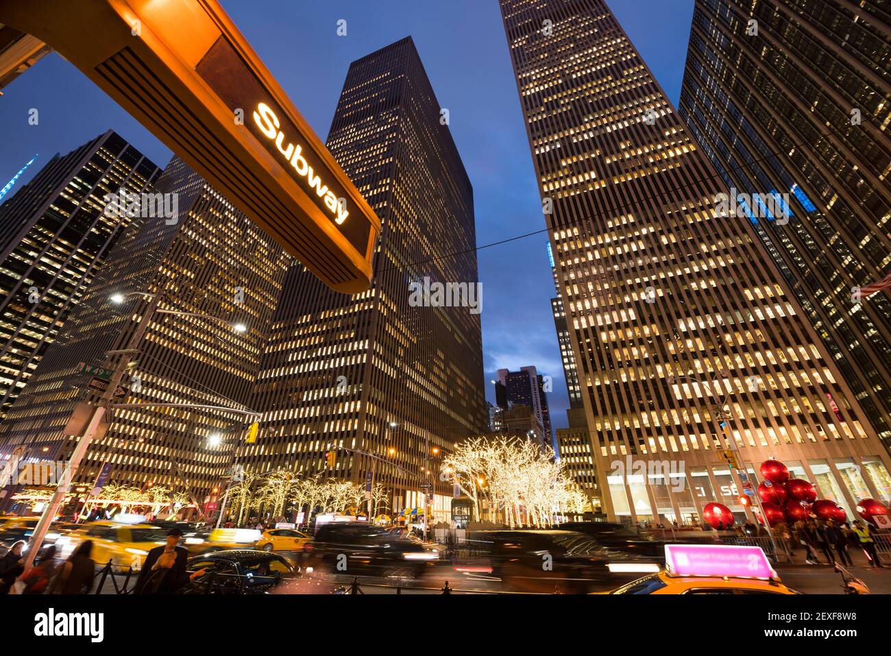 Midtown Sixth Avenue während der Weihnachtsfeiertage in der Nacht in New York City NY wird in den Reihen der Hochhäuser Verkehr durchfahren. Stockfoto