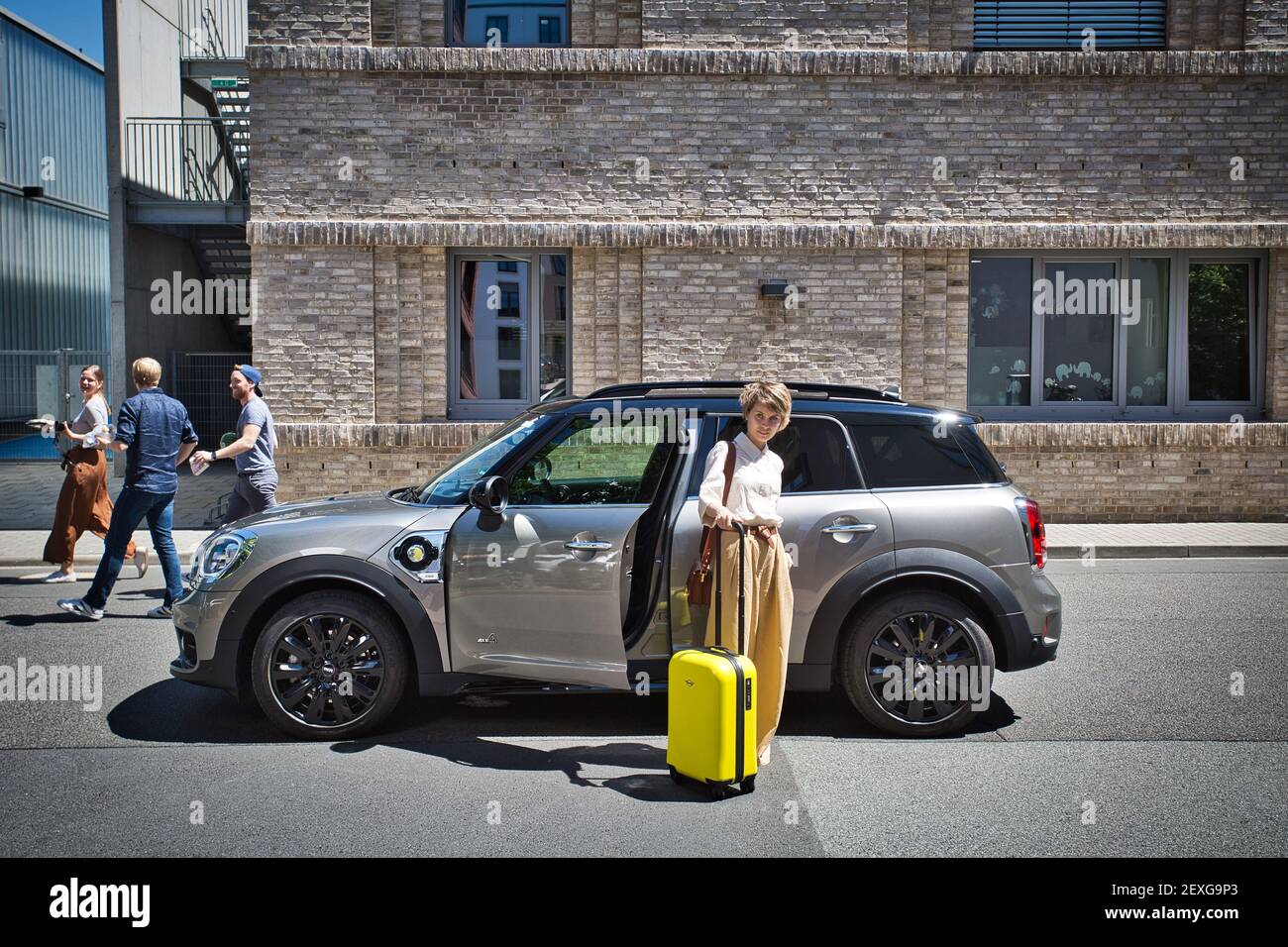 Frau mit Gepäck, die ihr Elektroauto in der Innenstadt im Freien in Frankfurt am Main, Hessen, Deutschland, lässt. Stockfoto