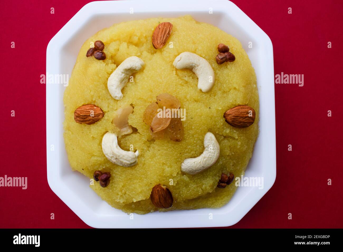 Traditionelle indische Dessert Süßigkeiten aus Grieß oder rawa bekannt als Kesari Bad mit Nüssen verziert garniert. südasiatische süß auf rotem Hintergrund. bl Stockfoto