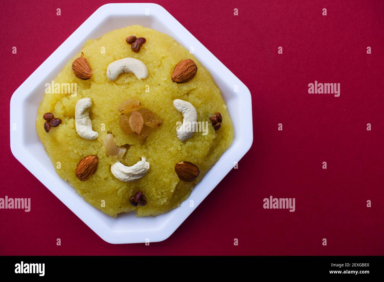 Traditionelle indische Dessert Süßigkeiten aus Grieß oder rawa bekannt als Kesari Bad mit Nüssen verziert garniert. südasiatische süß auf rotem Hintergrund. bl Stockfoto