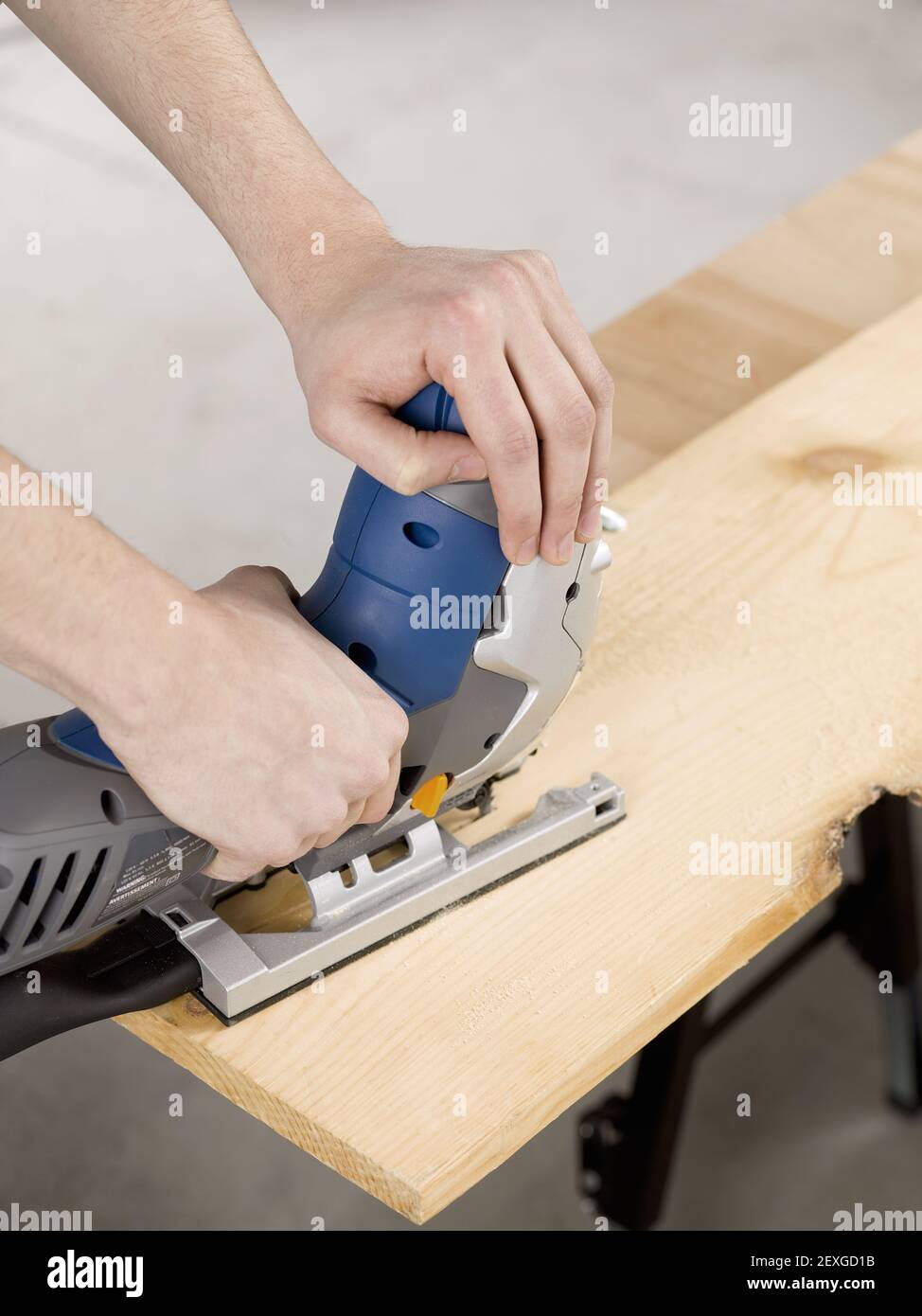 Hand mit elektrischen Stichsäge Holzblech zu schneiden Stockfoto