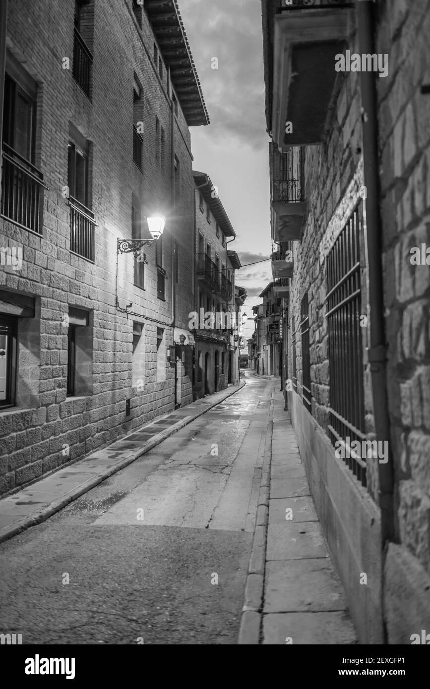 Eine vertikale Graustufenaufnahme einer Straße zwischen zwei Gebäuden Am Abend Stockfoto