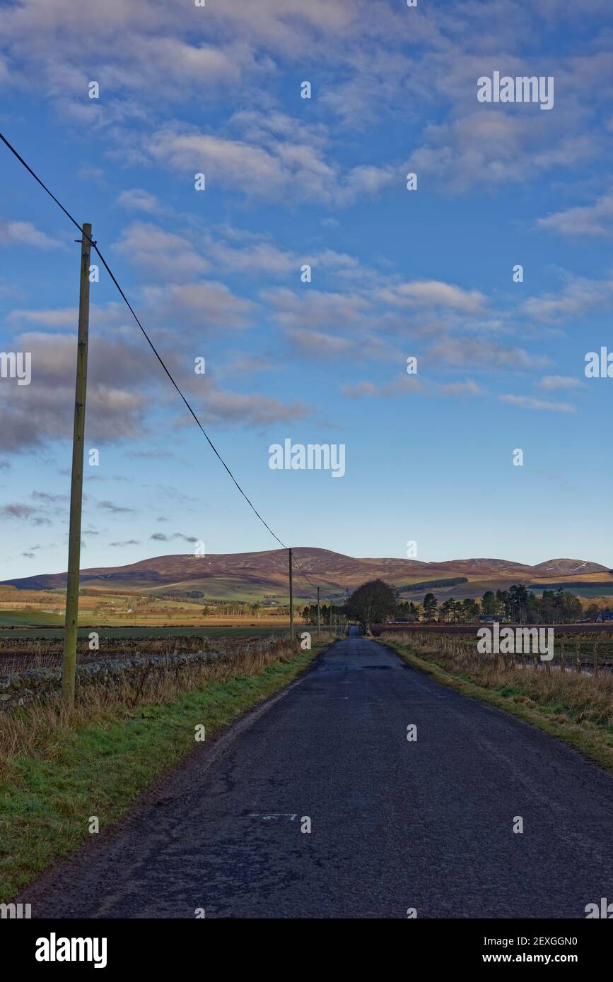 Morgenlicht auf den Hügeln des Angus Glens aus den Schatten des Valley Floor und der kleinen Scottish Road, die nach Glen Lethnot führt. Stockfoto