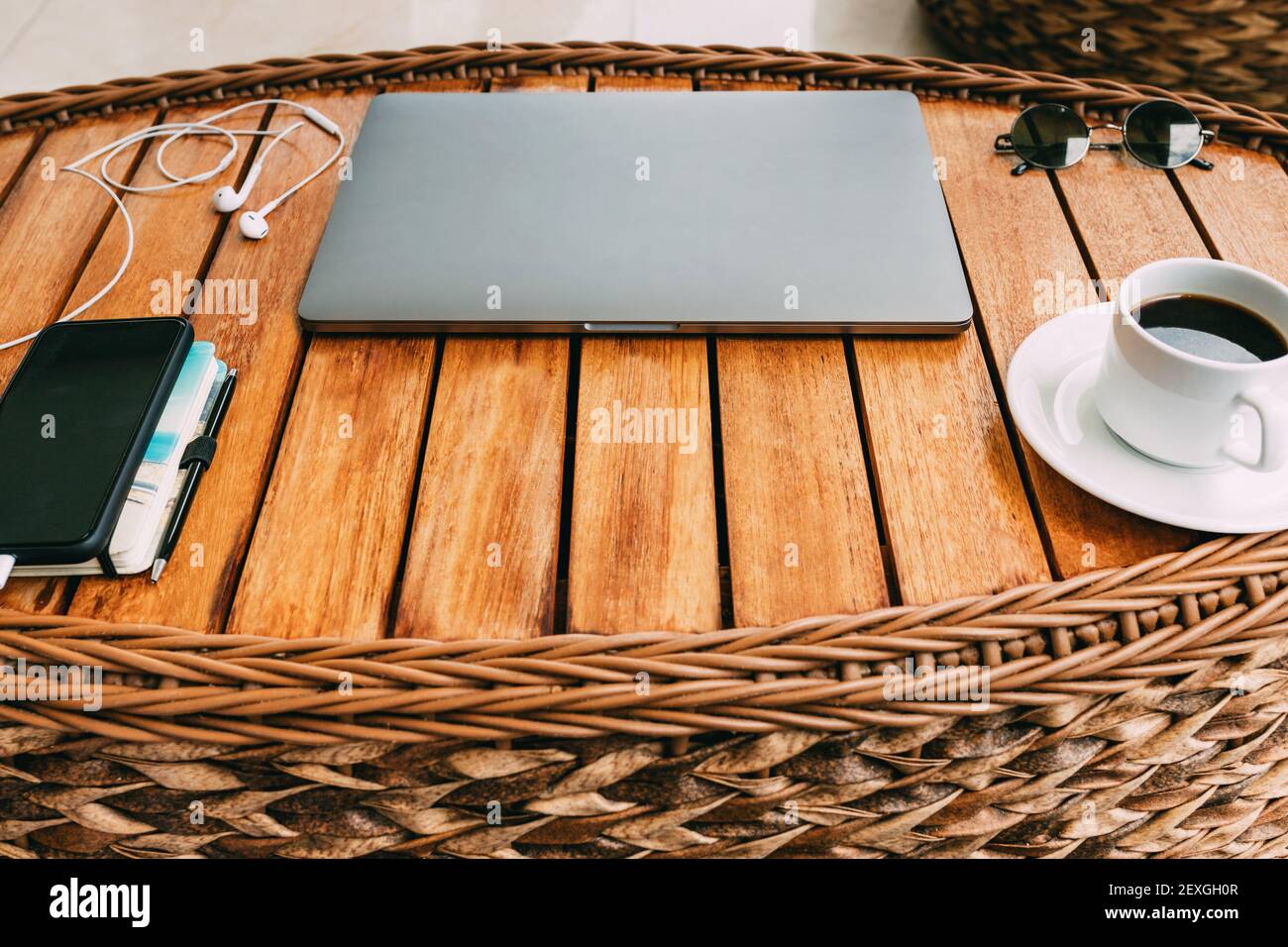Arbeitsplatz mit Laptop, auf braunem Holztisch mit Smartphone eine Tasse Kaffee und ein Notebook für die Aufnahme von Koffern. Draufsicht, Geschäftskonzept. Rem Stockfoto
