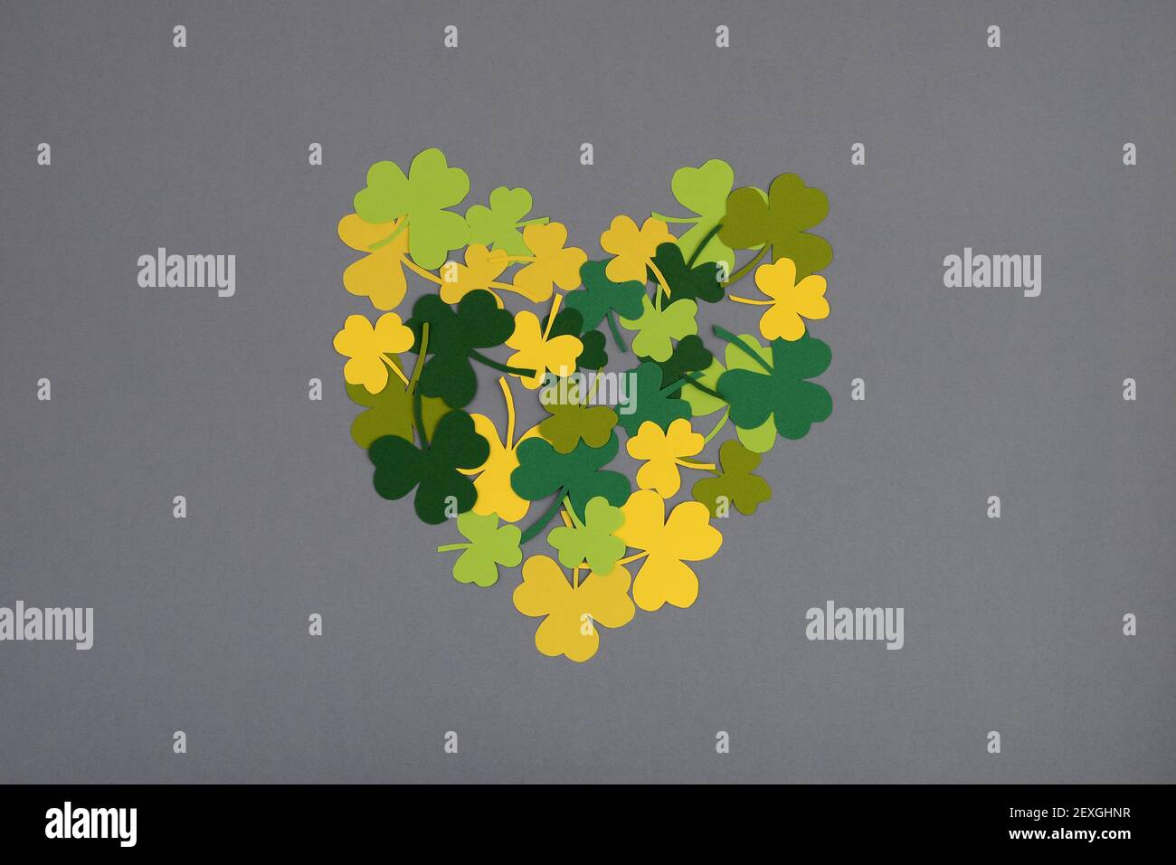 St. Patricks Day. Herzform von Kleeblättern auf grauem Hintergrund. Flach liegend, Draufsicht. Stockfoto