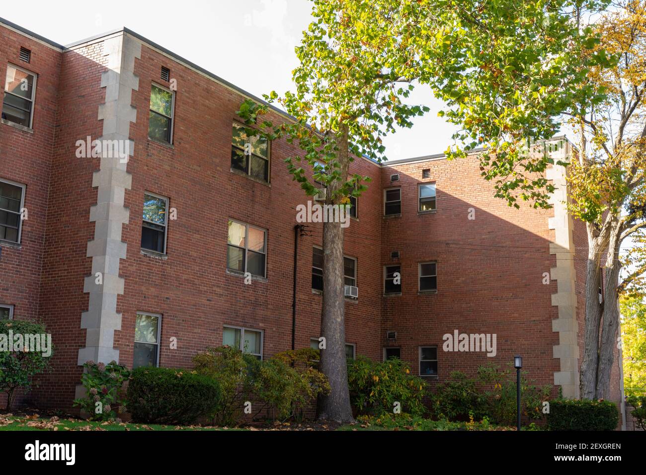 Schattige Seite eines generischen alten Wohnhauses, gemauerte Wohngebäude mit Betonquoins, horizontaler Aspekt Stockfoto