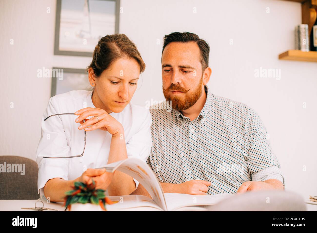 Mann und Frau lesen Buch zusammen mit ernsten Gesichtsausdruck Stockfoto