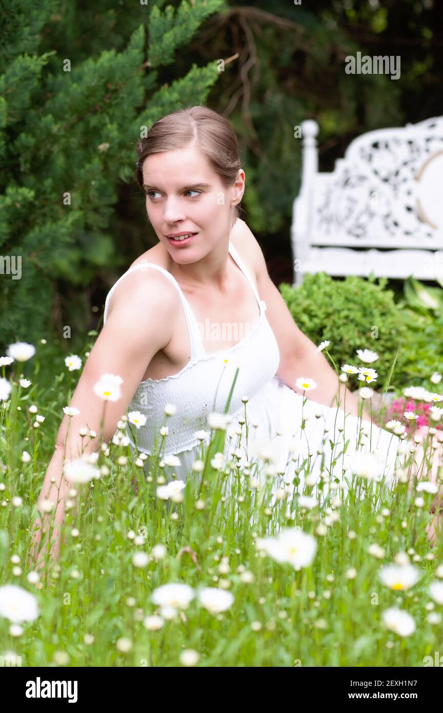 Attraktive Frau, die im Frühling auf einer Wiese sitzt Stockfoto