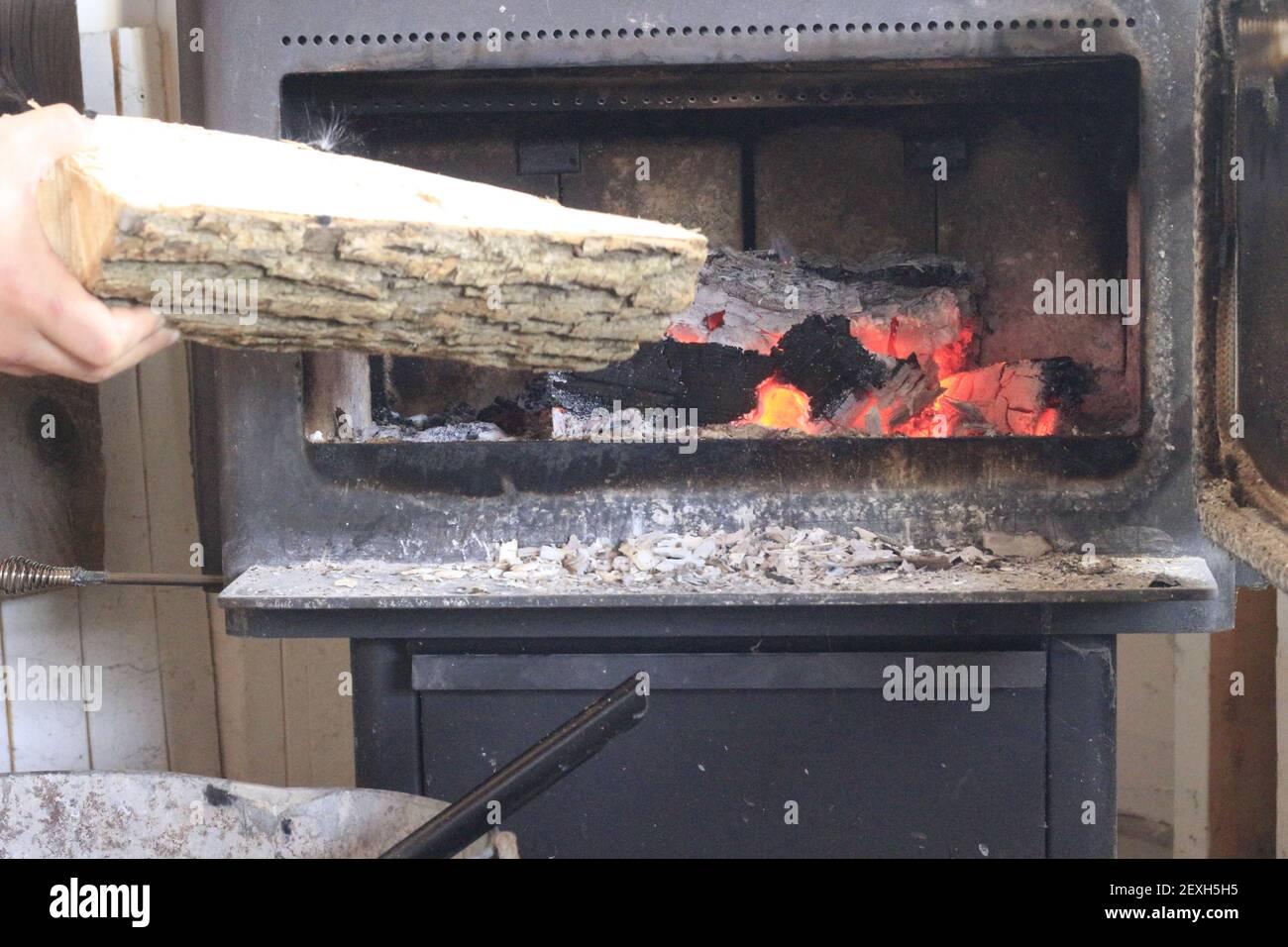 Hinzufügen von Holz in einen Holzofen während der kalten Wintermonate. Stockfoto