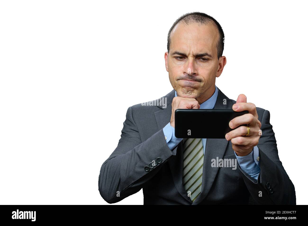 Reifer Mann mit Anzug und Krawatte, Blick auf sein Smartphone, enttäuscht und mit der Faust unter dem Kinn. Stockfoto