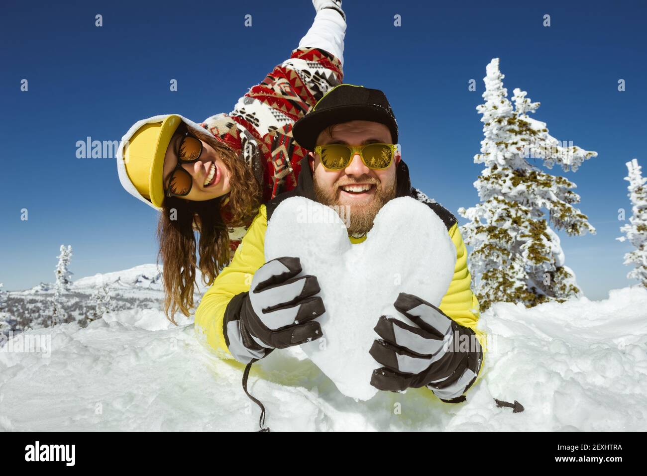 Romantisches Paar hat Spaß mit Herz des Schnees im Skigebiet. Winterurlaub Konzept Stockfoto