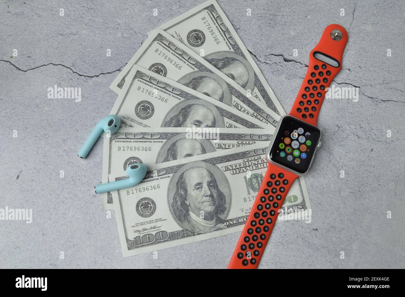 Klang, Malaysia: 5. März 2021 - eine Apfeluhr, Kopfhörer und Geldscheine auf grauem Hintergrund. Stockfoto