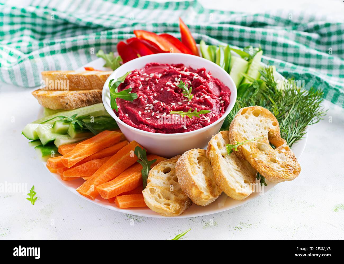 Gerösteter Rübenhummus mit Toast und Gemüse auf hellem Hintergrund. Beetroot Hummus. Stockfoto