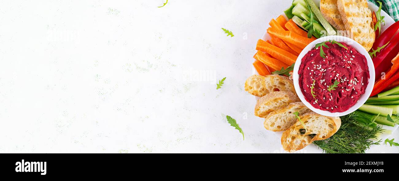 Gerösteter Rübenhummus mit Toast und Gemüse auf hellem Hintergrund. Beetroot Hummus. Draufsicht, oben, Banner Stockfoto